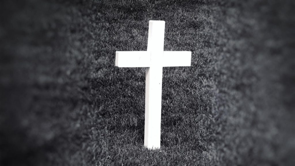 black and white photo of white cross in grass