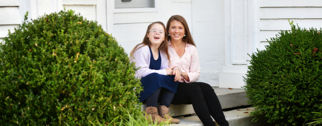 Penny and Amy Julia sitting together on a porch step and smiling at the camera