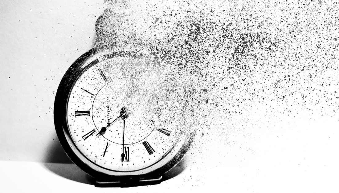 black and white image of an old fashioned alarm clock with a part of it disintegrating 