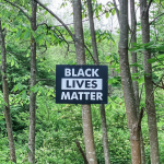 sign in a forest nailed to a tree that says Black Lives Matter