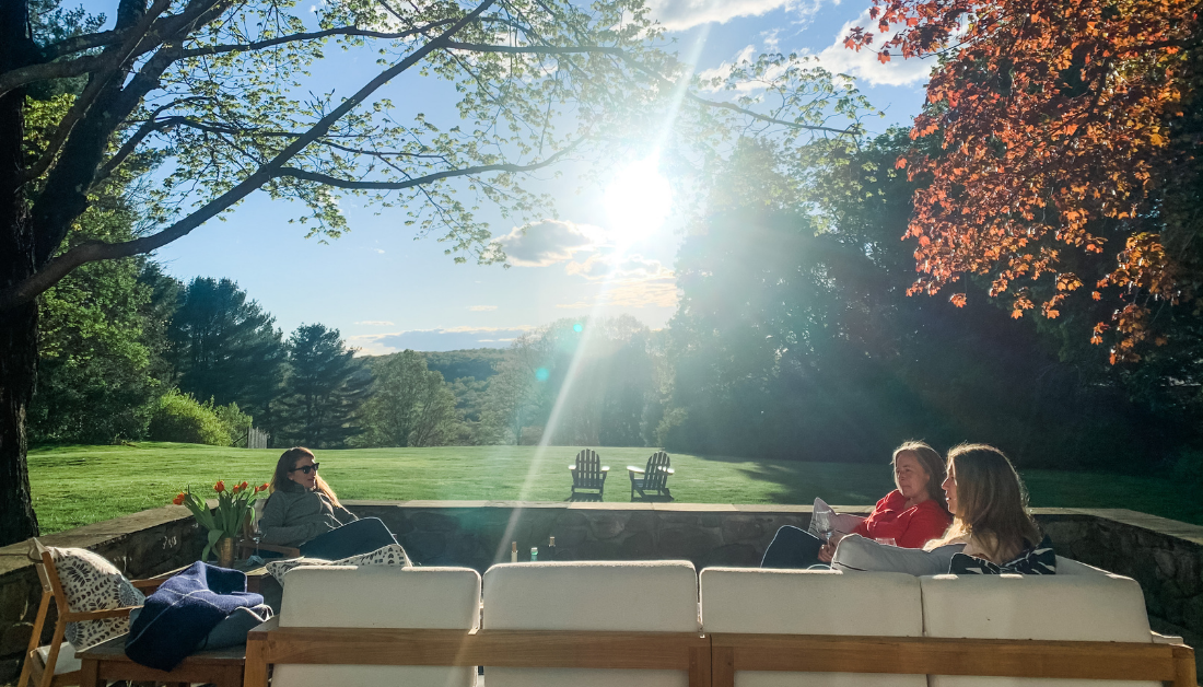 picture of women sitting on a deck with sunlight filtering through trees