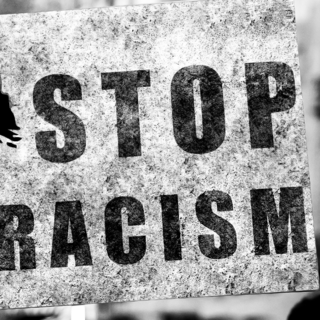 black and white photo of a sign that says Stop Racism