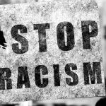 black and white photo of a sign that says Stop Racism