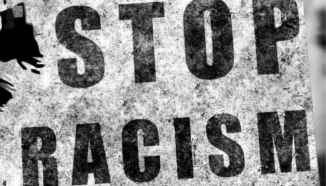 black and white anti-racism photo of a sign that says Stop Racism