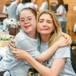 picture of Penny and Katherine Wolf at Hope Heals Camp smiling at the camera with their harms around each other