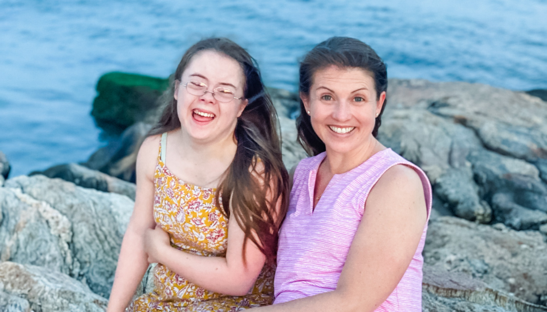 Penny and Amy Julia sitting on rocks next the ocean. Penny is laughing and Amy Julia is smiling at the camera