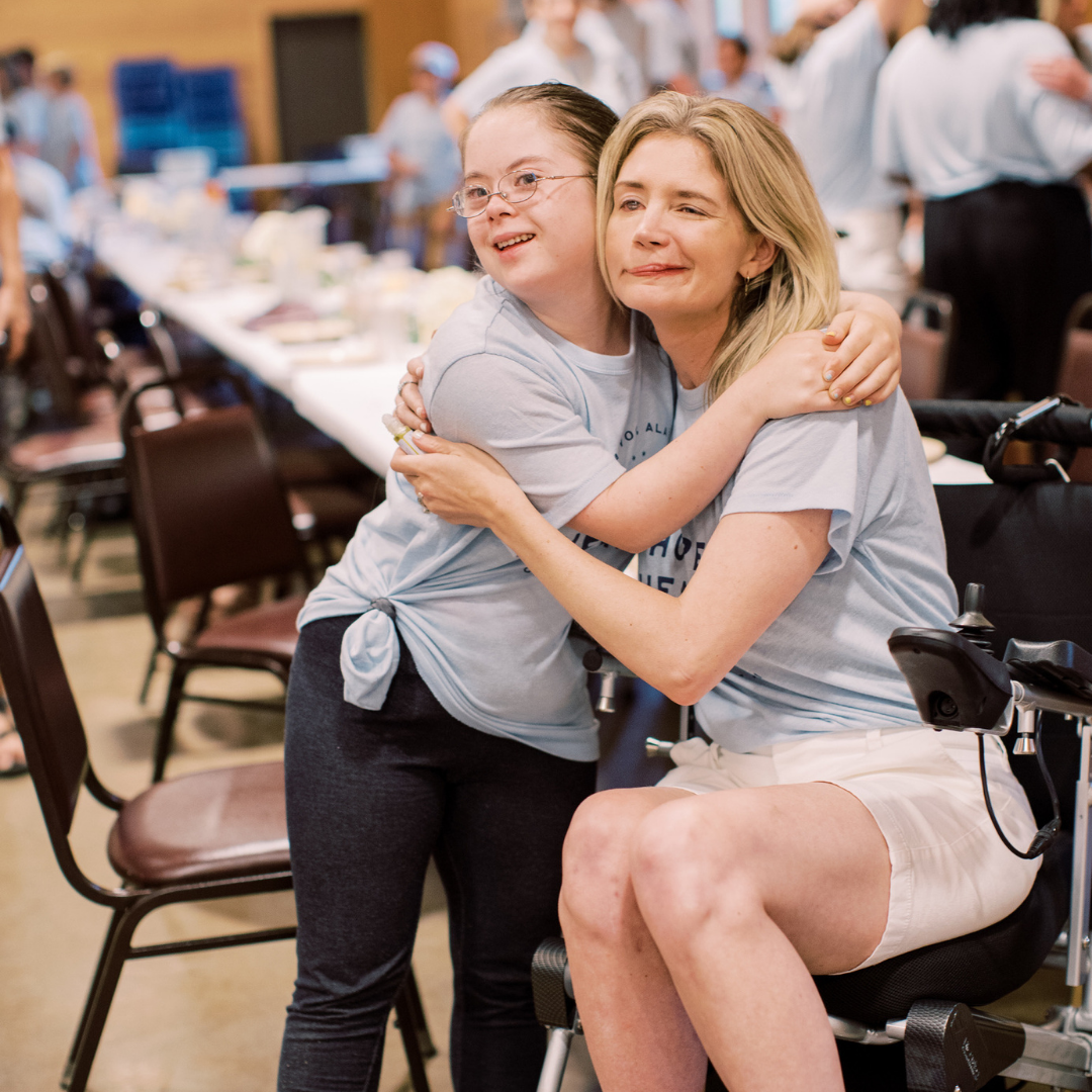 Penny, who has Down syndrome, and Katherine Wolf, who is sitting in a wheelchair, giving each other a hug at Hope Heals Camp