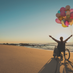 Person with a disability in a wheelchair with colored balloons at the beach