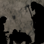 Mary, Joseph and baby Jesus in the manger silhouetted against a dark wall