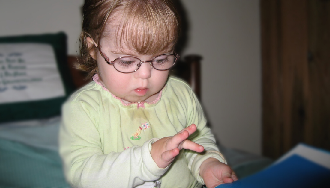 Penny as a toddler extending her finger to point at a book.