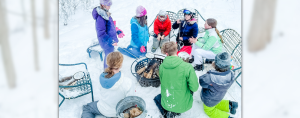 teens and children in the snow gathered around a firepit