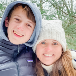 William and Amy Julia stand in a forest and are wearing winter coats and hats.