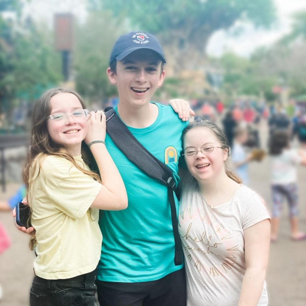 Marilee, William, and Penny smile at the camera as they stand in a thoroughfare at Disney