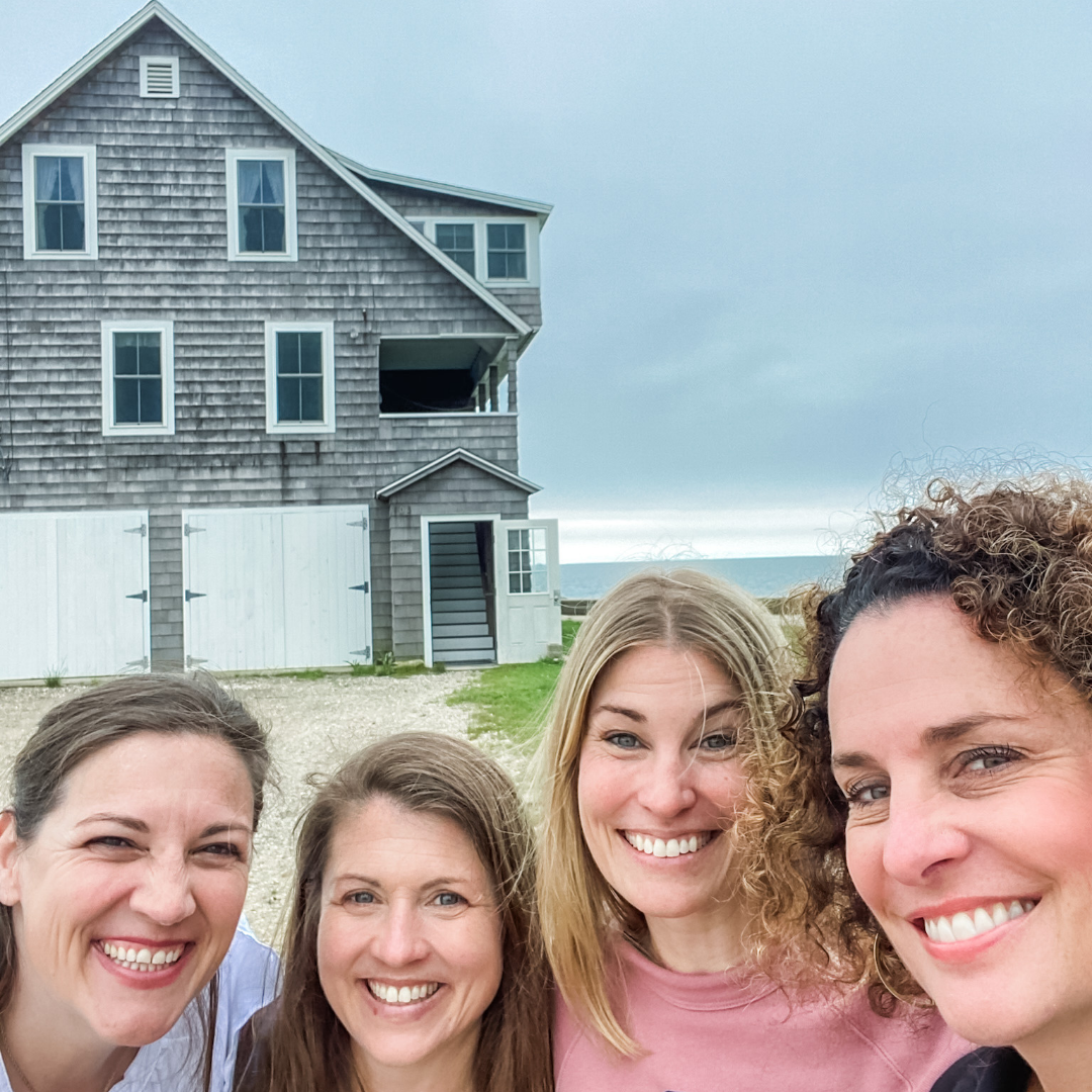 Amy Julia stands with three writer friends with a house and the ocean in the background