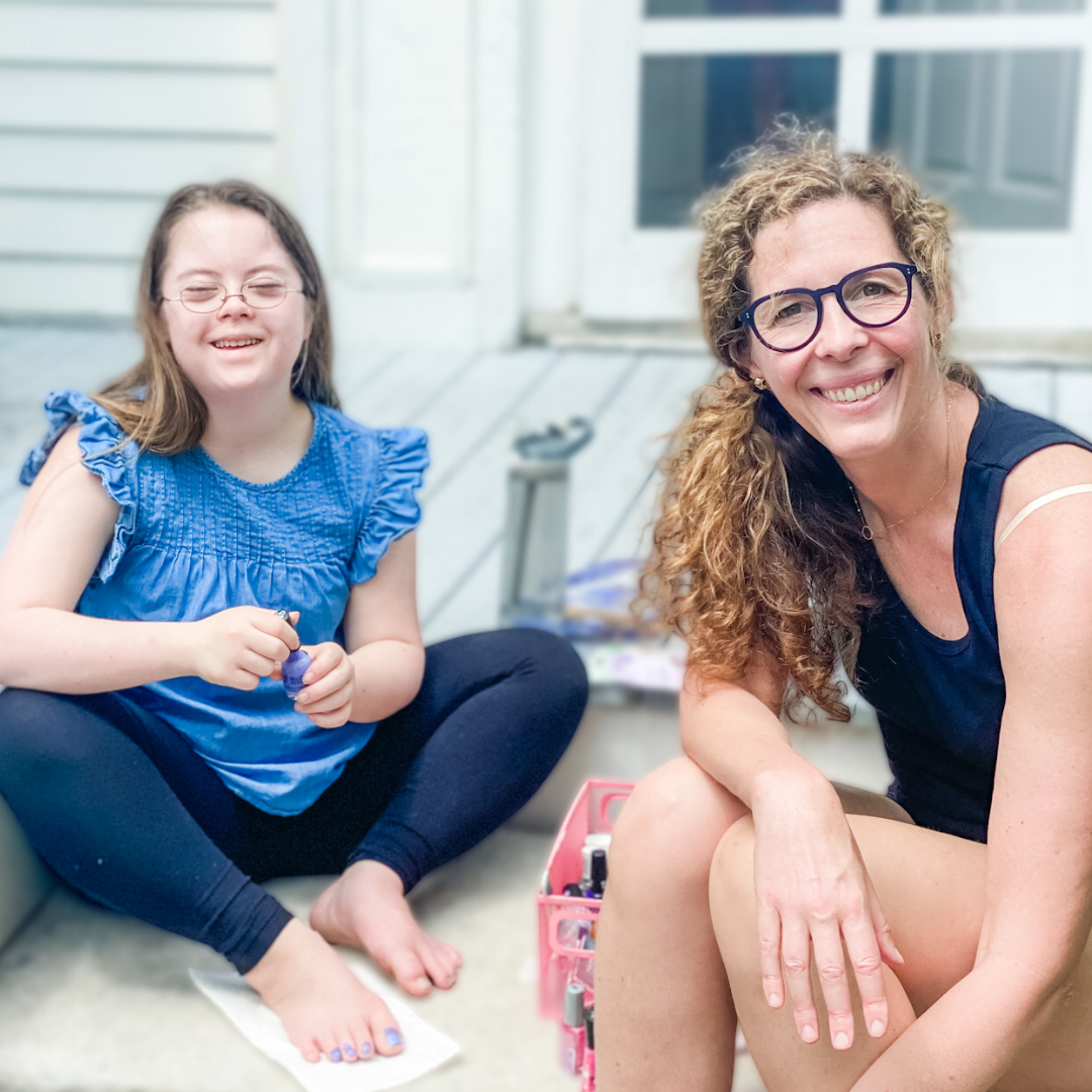 Penny and Elizabeth sit on the porch and smile at the camera. They are ready to paint their toenails.