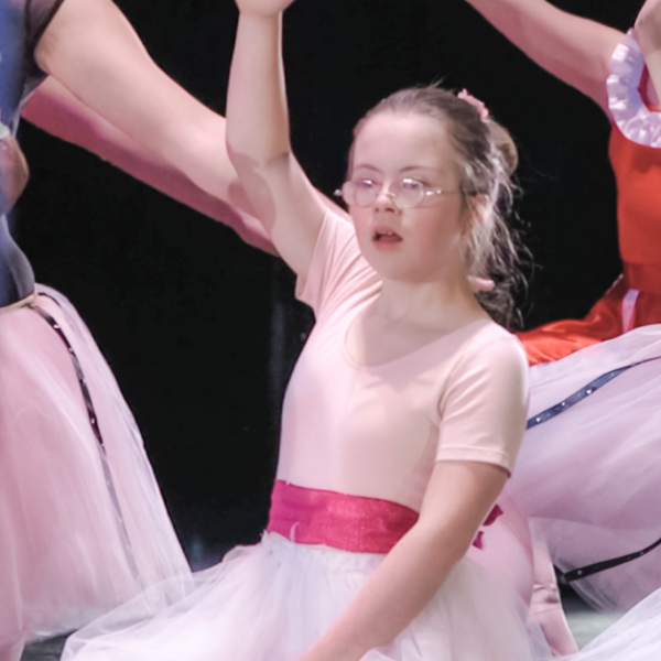 Penny is dancing on stage in a pink ballet costume. The picture was taken when she was several years younger.