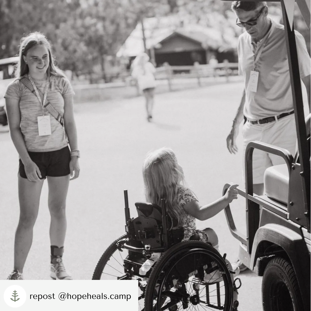 A young girl using a wheelchair looks up at Peter who is the golf cart driver
