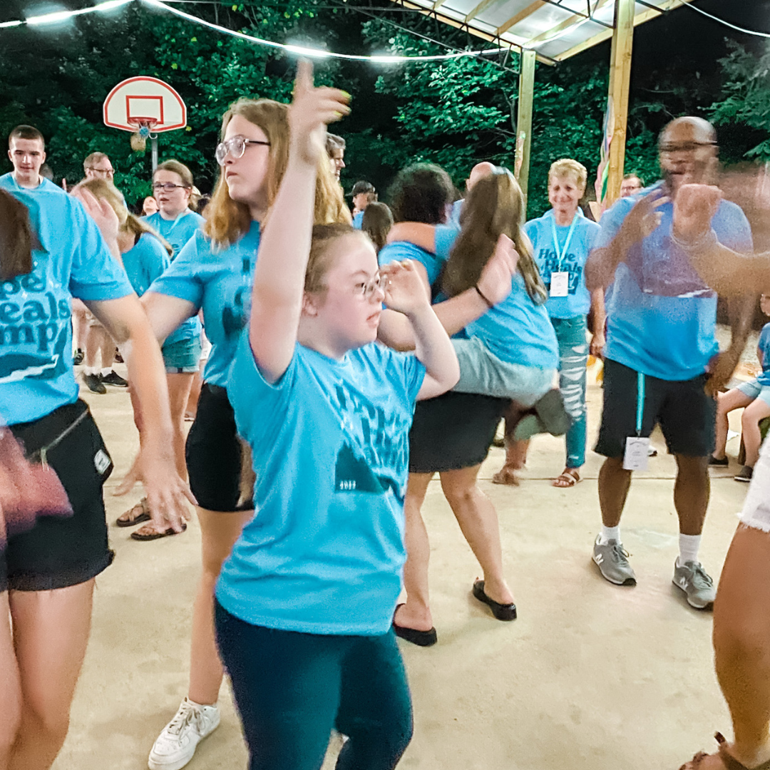 Penny and other campers wearing blue shirts dancing at an outside dance party