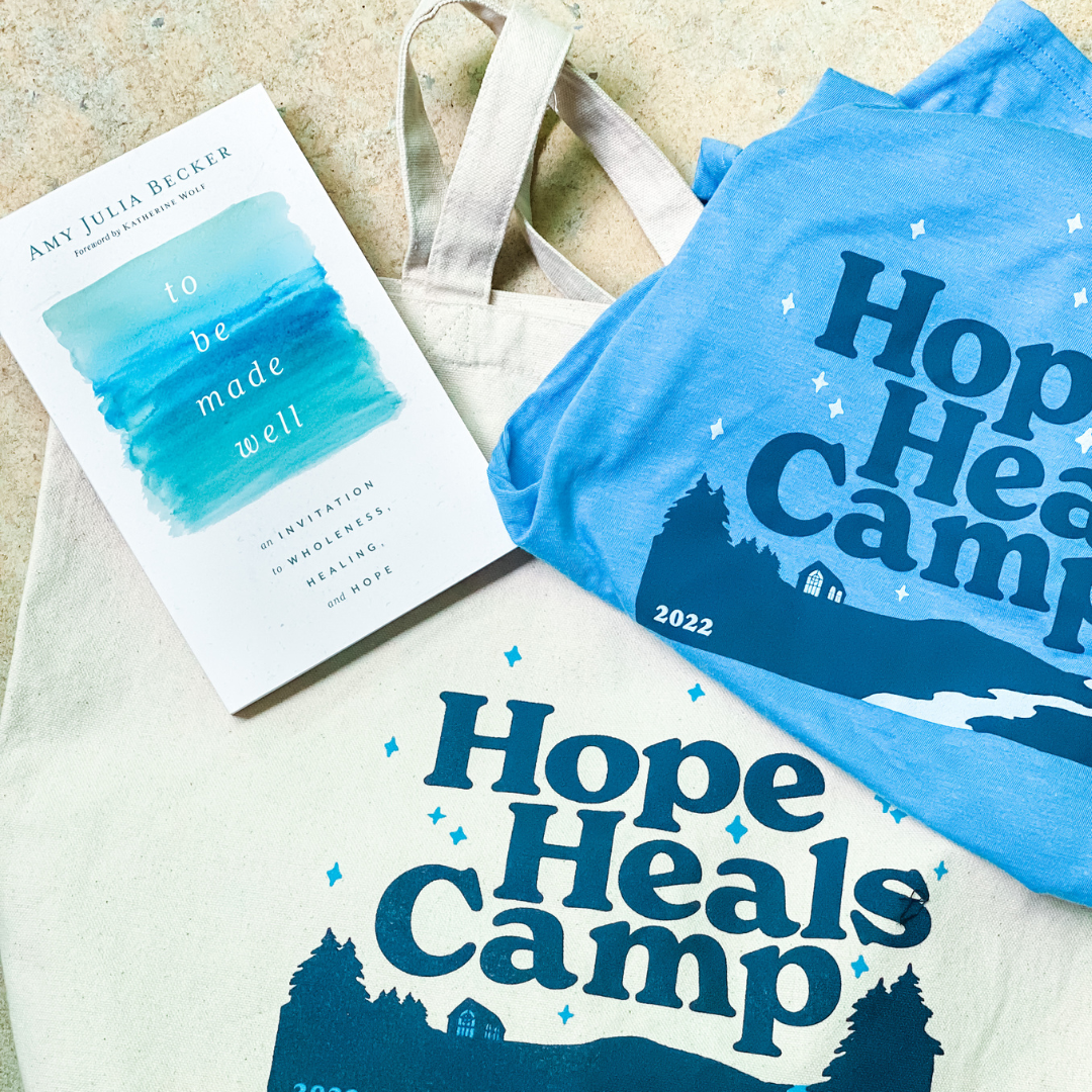 a copy of To Be Made Well and a blue Hope Heals Camp t-shirt are on top of a Hope Heals Camp tote bag