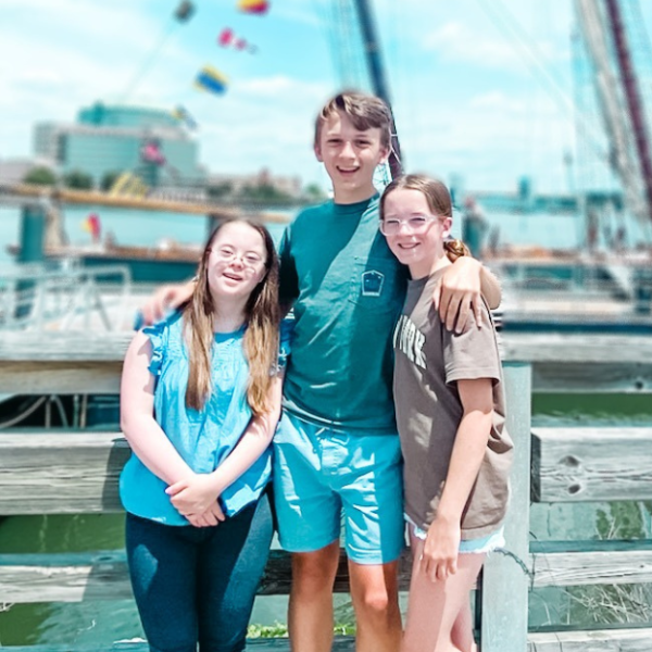 Penny, William, and Marilee stand in front of a schooner on a sunny day