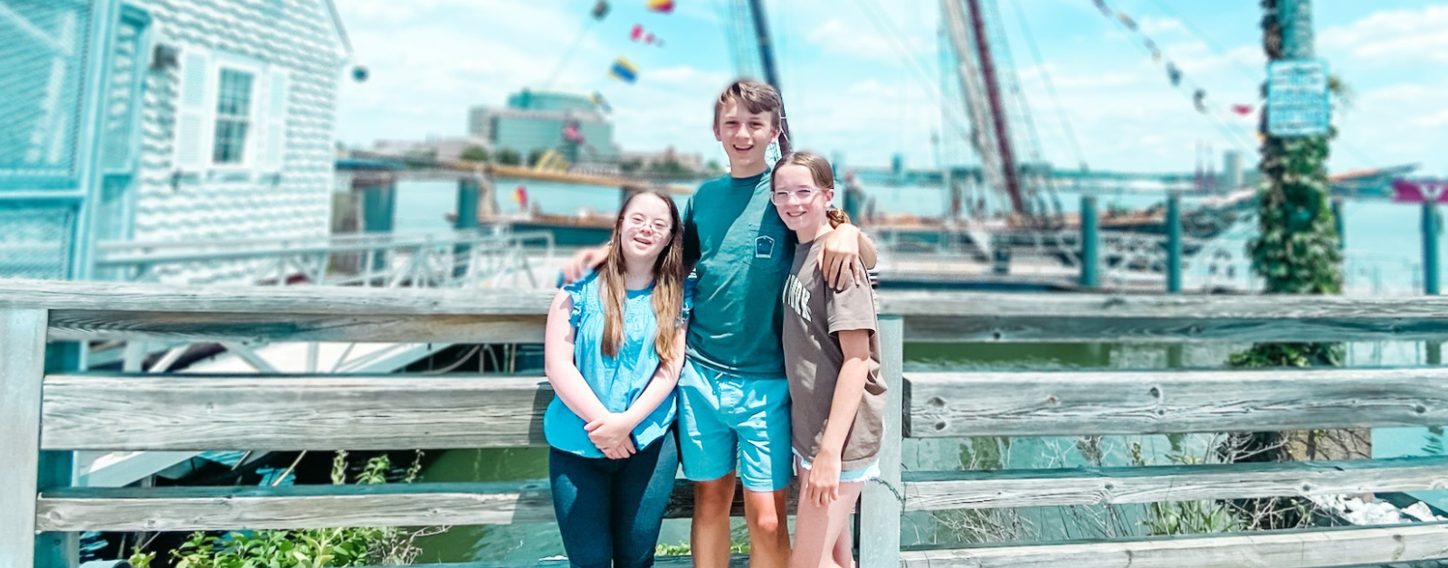 Penny, William, and Marilee stand in front of a schooner on a sunny day