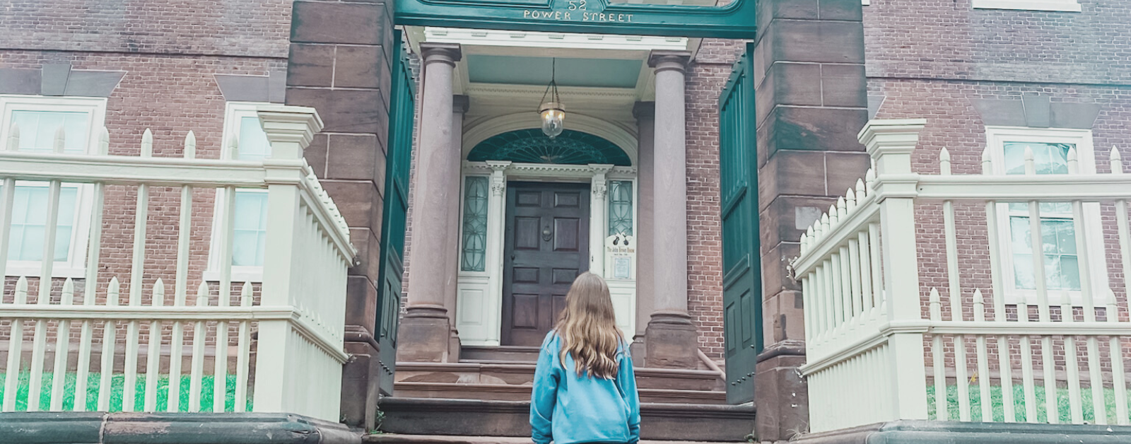 Marilee stands in front of the red brick John Brown home