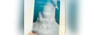hand holding the book The Song of Our Scars