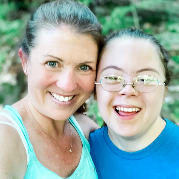 Amy Julia and Penny take a selfie in the forest. They smile widely at the camera and lean their heads against each other