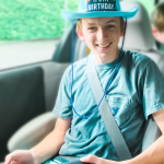 William sits in a van. He wears a blue hat that says, "It's my birthday."