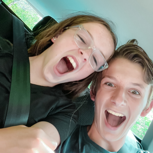 Marilee and William make excited, silly faces for selfie in a vehicle