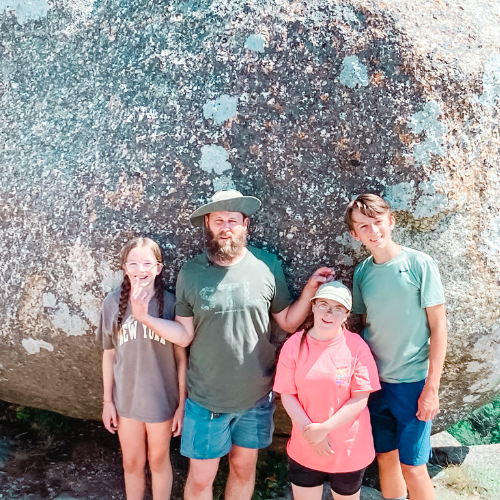 Marilee, friend, Penny, and William pose in front of a large rock