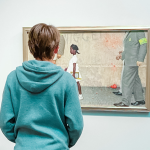 William stands with his back to the camera and looks at a Ruby Bridges painting at the Norman Rockwell Museum