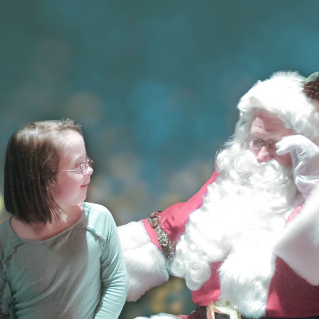 young girl with a disability sits on Santa and looks at him with a small smile