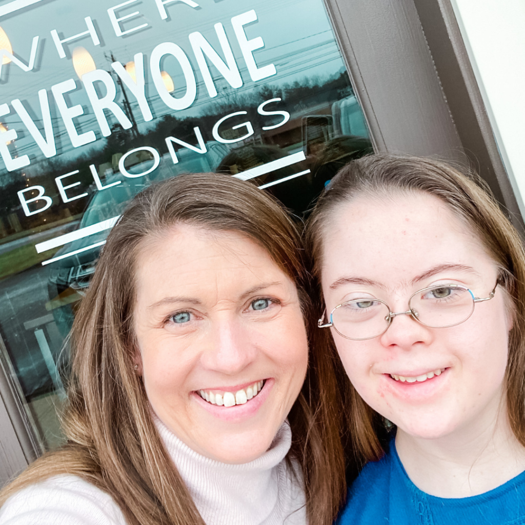 Amy Julia and Penny smile and take a selfie in front of BeanZ and Co. "Where Everyone Belongs" is stenciled on the glass door behind them.