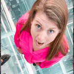 Amy Julia stands on the glass-encased floor of One Vanderbilt. Her mouth and eyes are wide open and she looks up at a camera high above her.