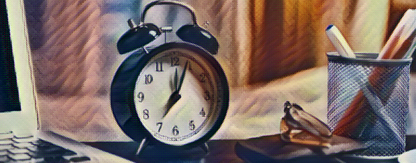painted filter over a photo of an alarm clock on a desk next to a laptop