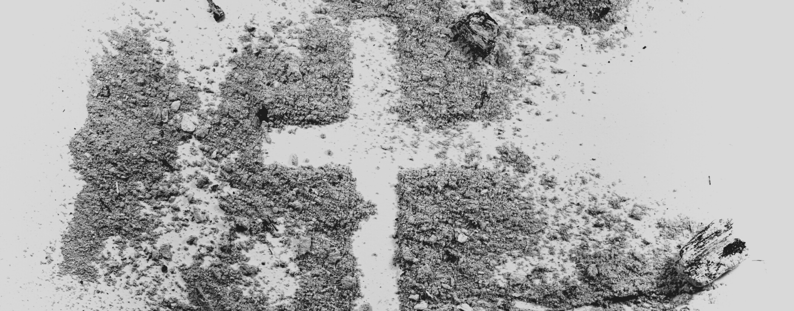 photo of a cross drawn in a pile of ash