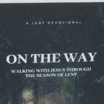 photo of the devotional On the Way: Walking with Jesus Through the Season of Lent on a black table with a bookshelf blurred in the background