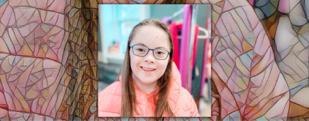 indoor photo of Penny smiling at the camera and wearing glasses and a salmon coat