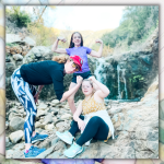 photo of Elizabeth, Marilee, and Penny flexing their arms as they stand and sit on rocks in front of a small waterfall