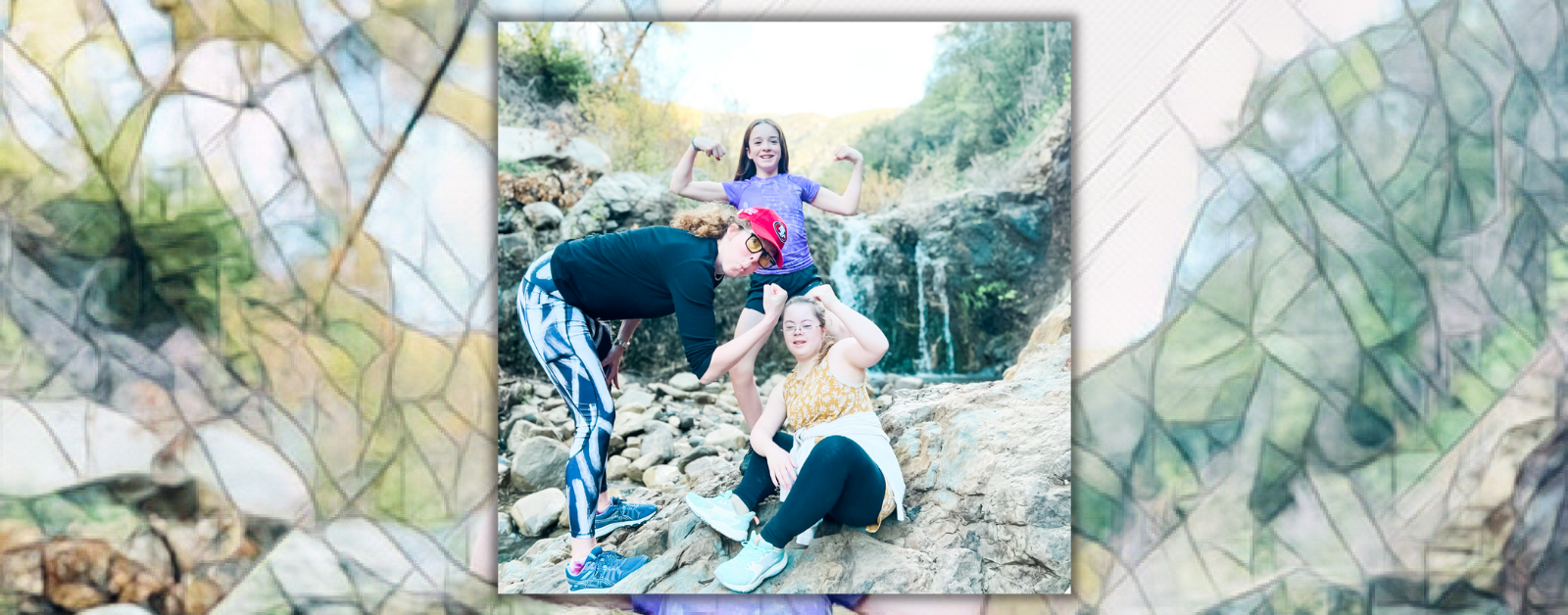 photo of Elizabeth, Marilee, and Penny flexing their arms as they stand and sit on rocks in front of a small waterfall