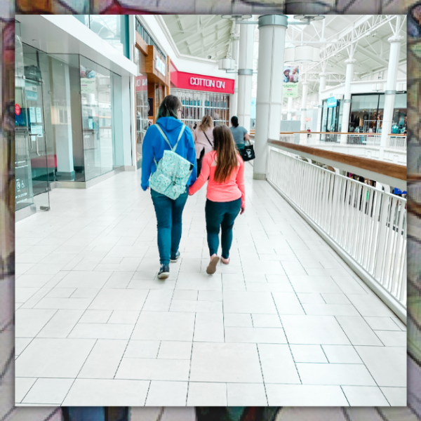 photo of a friend and Penny holding hands and walking away from the camera in a mall