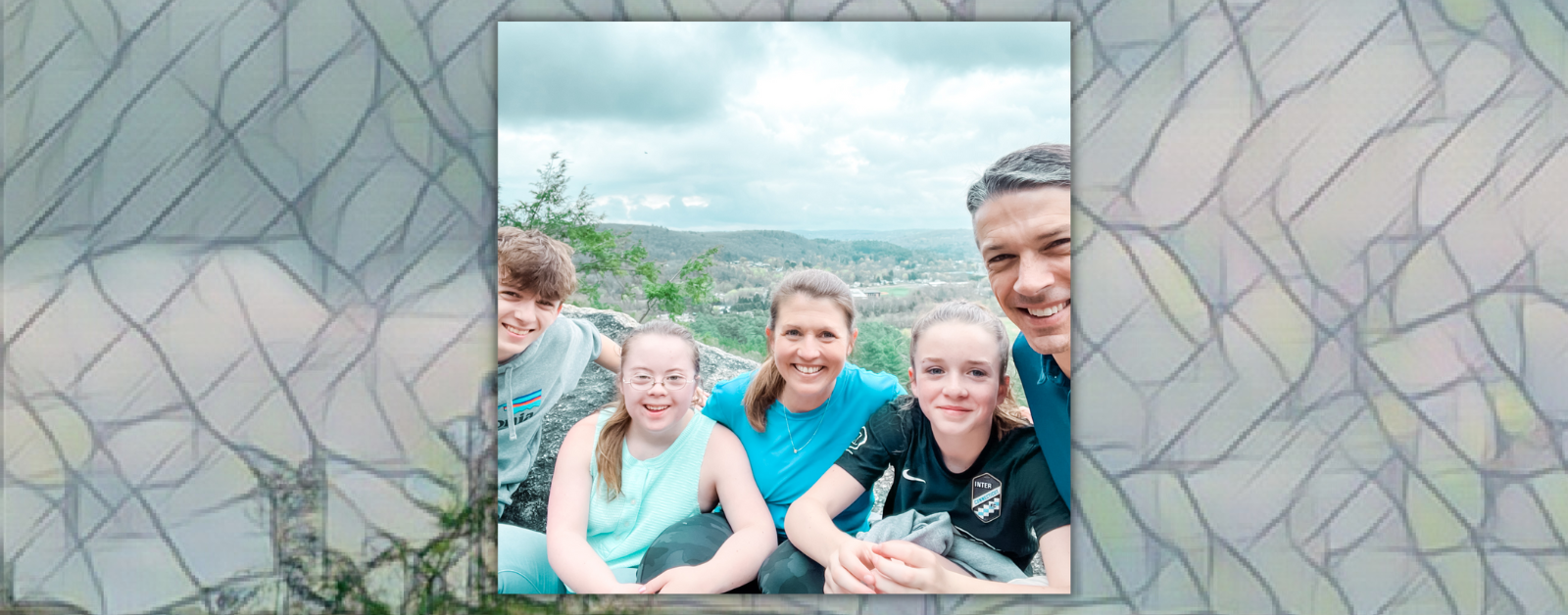 William, Penny, Amy Julia, Marilee, and Peter smile for a selfie on a rock outcropping overlooking a valley