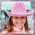 photo of Amy Julia smiling and wearing a pink cowboy hat and peach raincoat