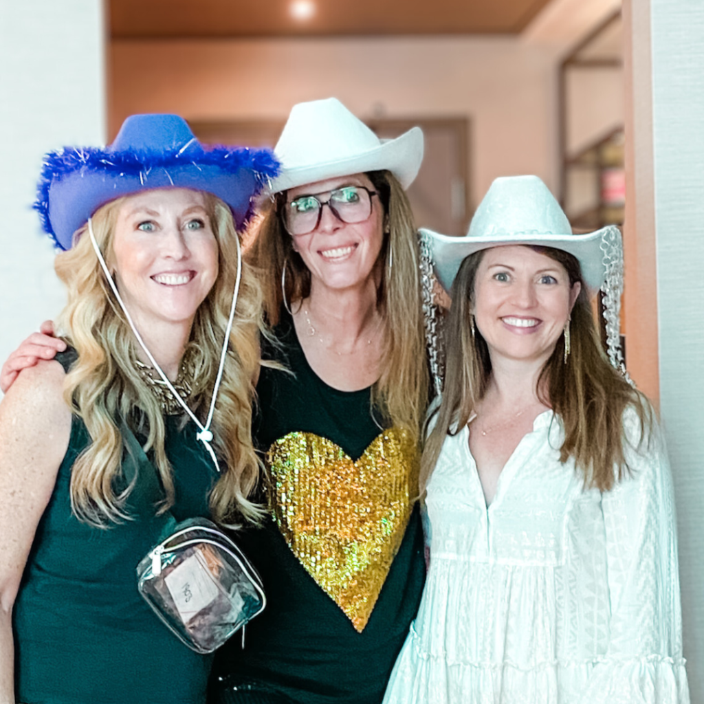 Amy Julia and two friends wear cowboy hats and smile for the camera