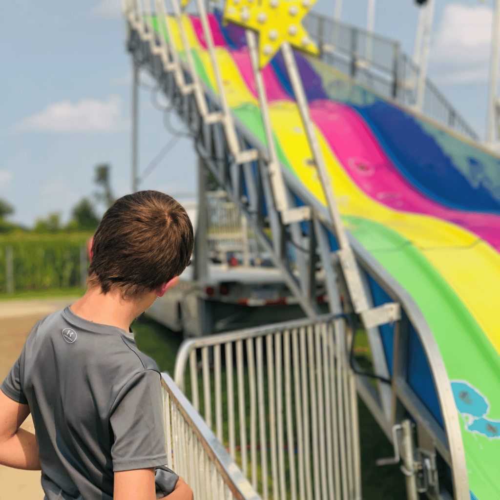 photo of a young teen looking a colorful slide at the county fair