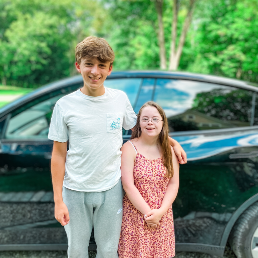 William and Penny stand together in front of a car