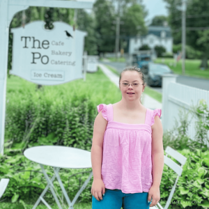 Penny poses outside in front of a sign for The Po Cafe 