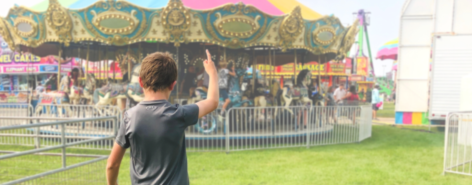 photo of a young teen pointing to a colorful carousel