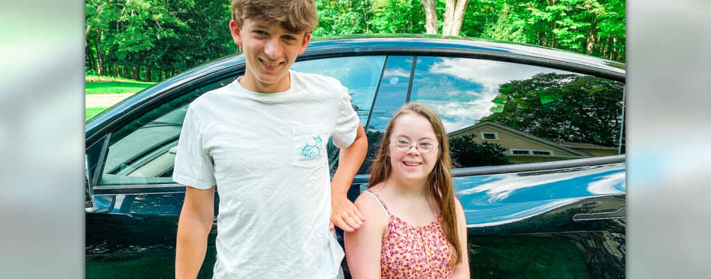 William and Penny stand together in front of a car.